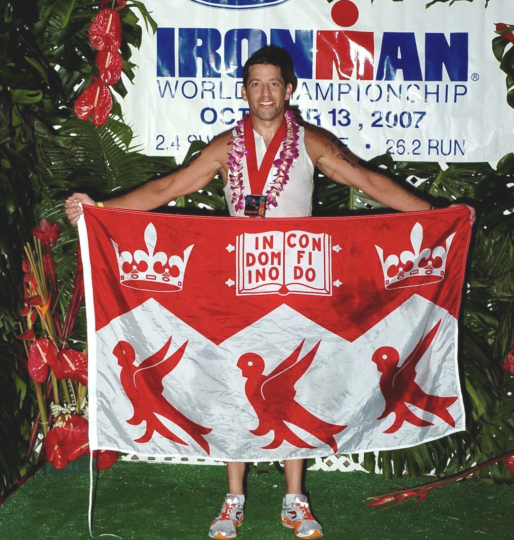 Jordan Waxman holding a McGill flag at an Ironman Triathlon