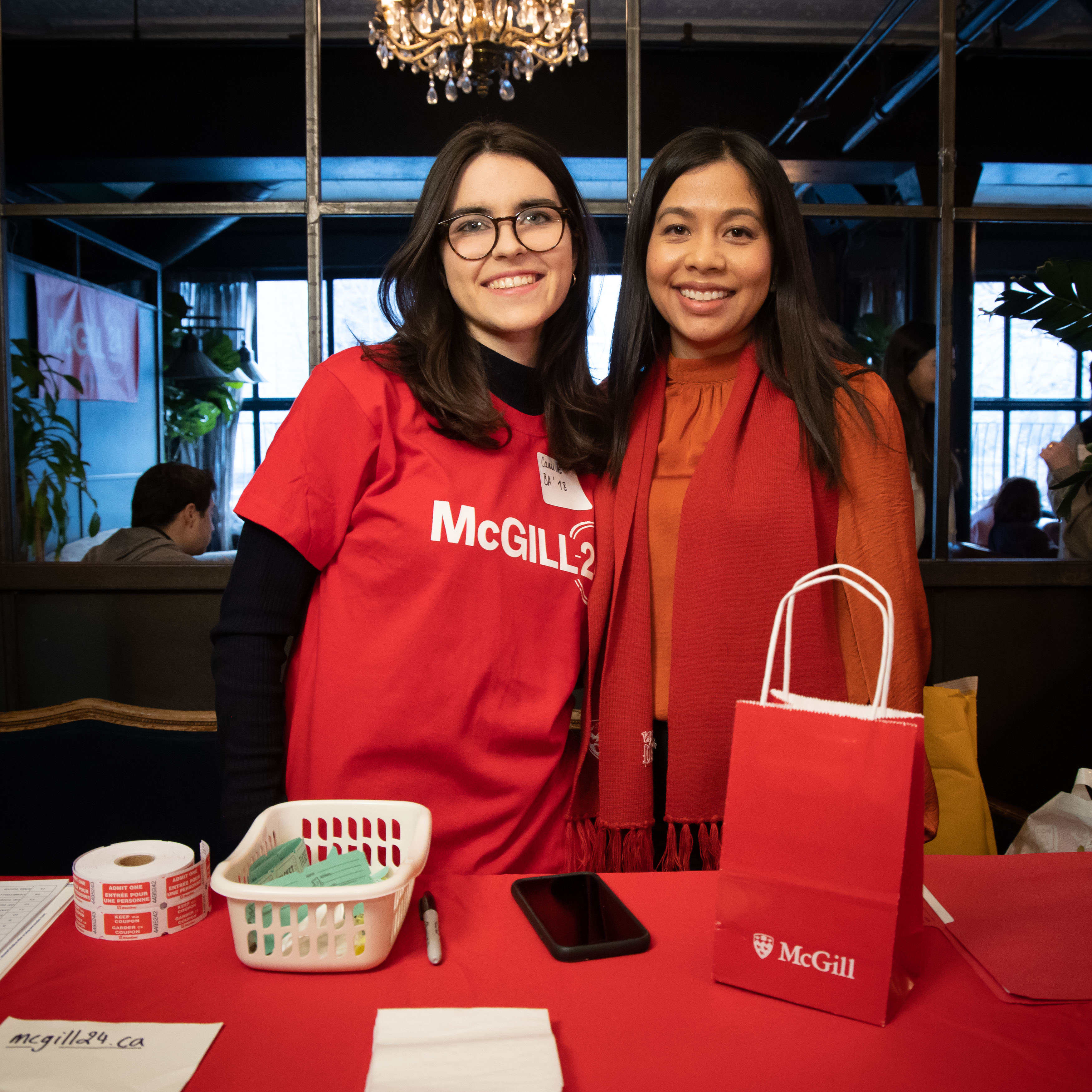 Two individuals in McGill attire standing in front of a McGill gift bag