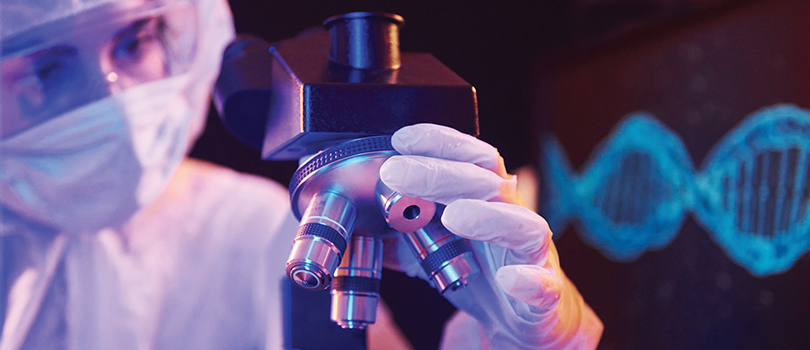 Researcher in PPE using microscope