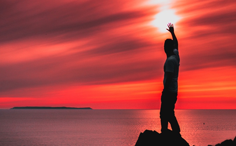 Person standing by ocean at sunset