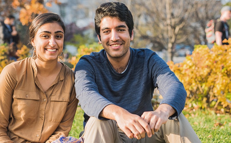 Two students in front of an autumn background 