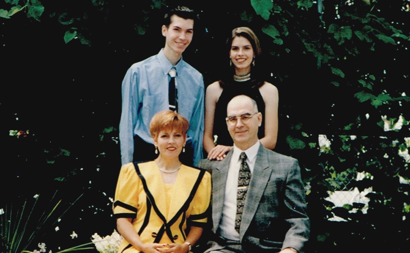 Catherine Dufour et son frère, tous deux debout, prennent la pose derrière leur mère et leur père assis devant des arbres en 1997