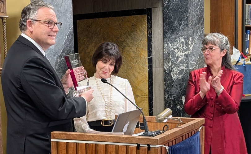 A person holding an award and standing at a podium.