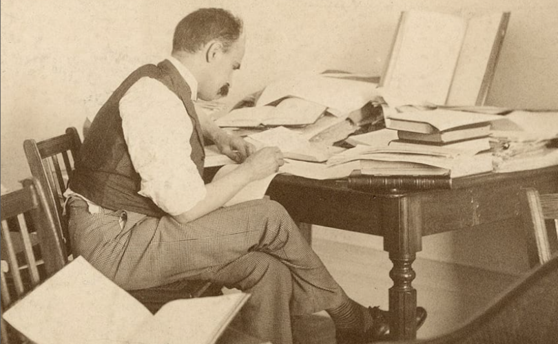 A person sitting at a desk with a pile of books.