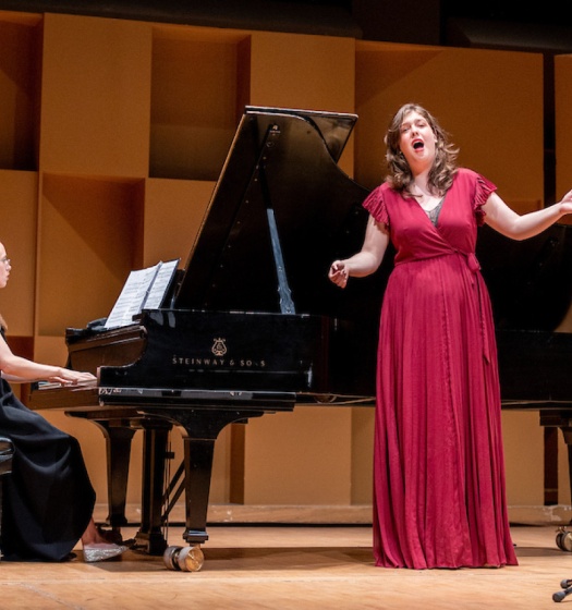 Individuals on stage, one singing and one playing the piano
