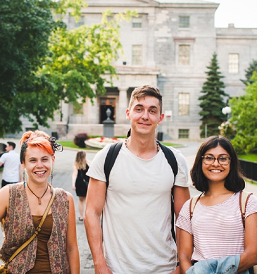 Three students standing on the pathway in front of the McCall MacBain building.
