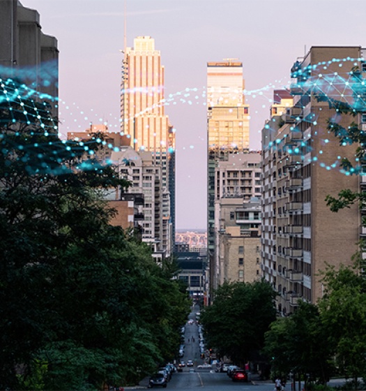 An urban street flanked by tall buildings with digital blue network lines and nodes superimposed, symbolizing connectivity or smart city technology. 